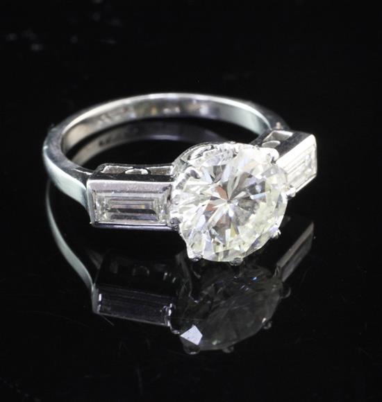 An early to mid 20th century platinum and single stone diamond ring with baguette cut diamond set shoulders, size I.